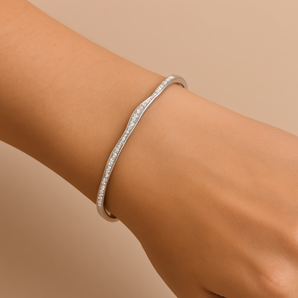 Silver bracelet on a wrist against a beige background