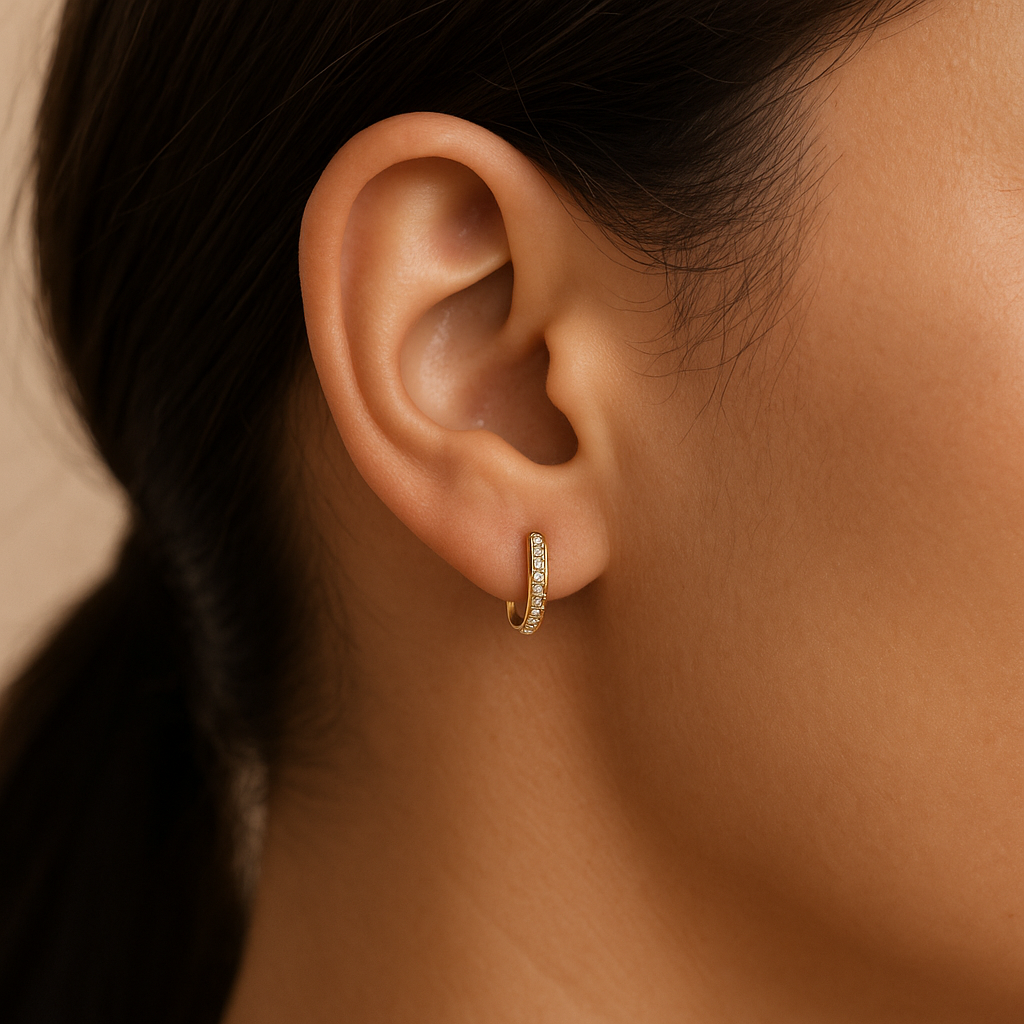 Close-up of an ear wearing a gold earring with a blurred background