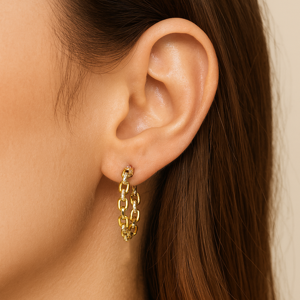 Gold chain earring worn by a person with brown hair.