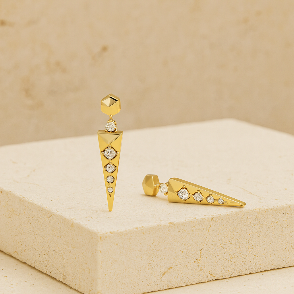 Gold earrings with diamond accents on a beige stone surface