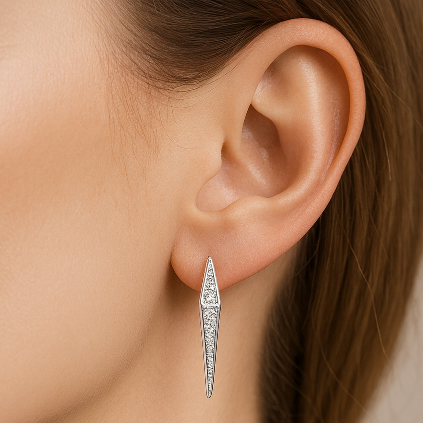 Close-up of a person wearing silver earrings with a neutral background
