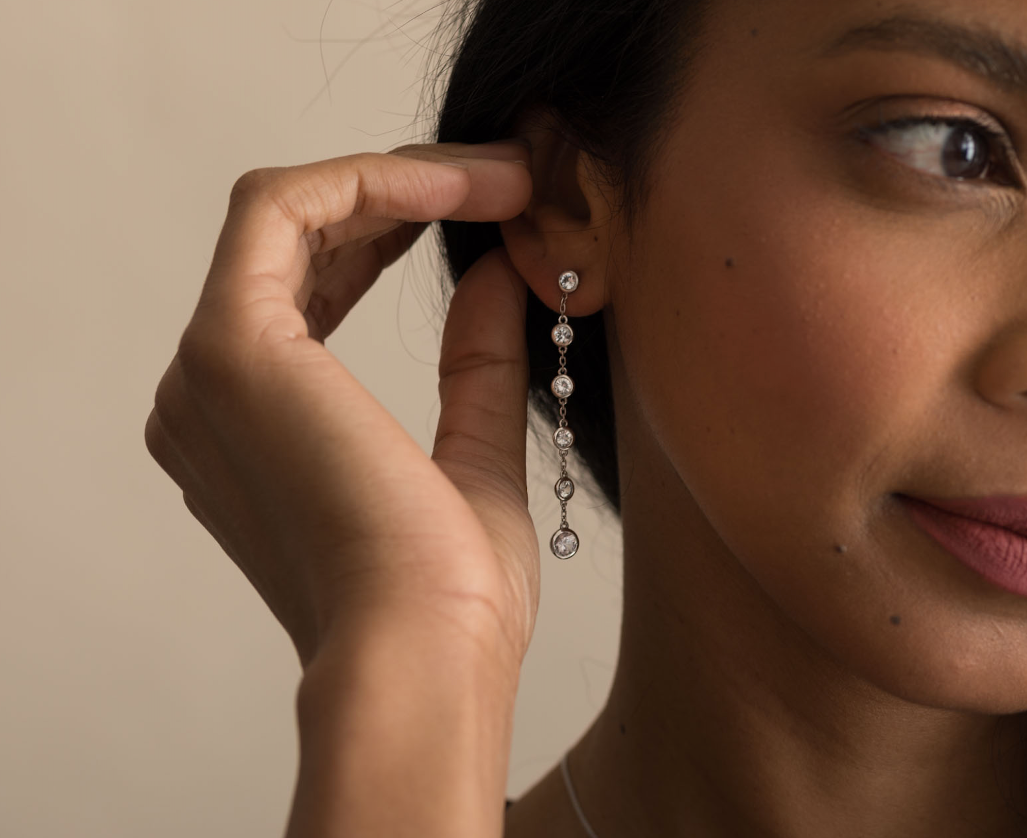 Close-up of woman wearing sterling silver gemstone dangle earrings with white sapphires.