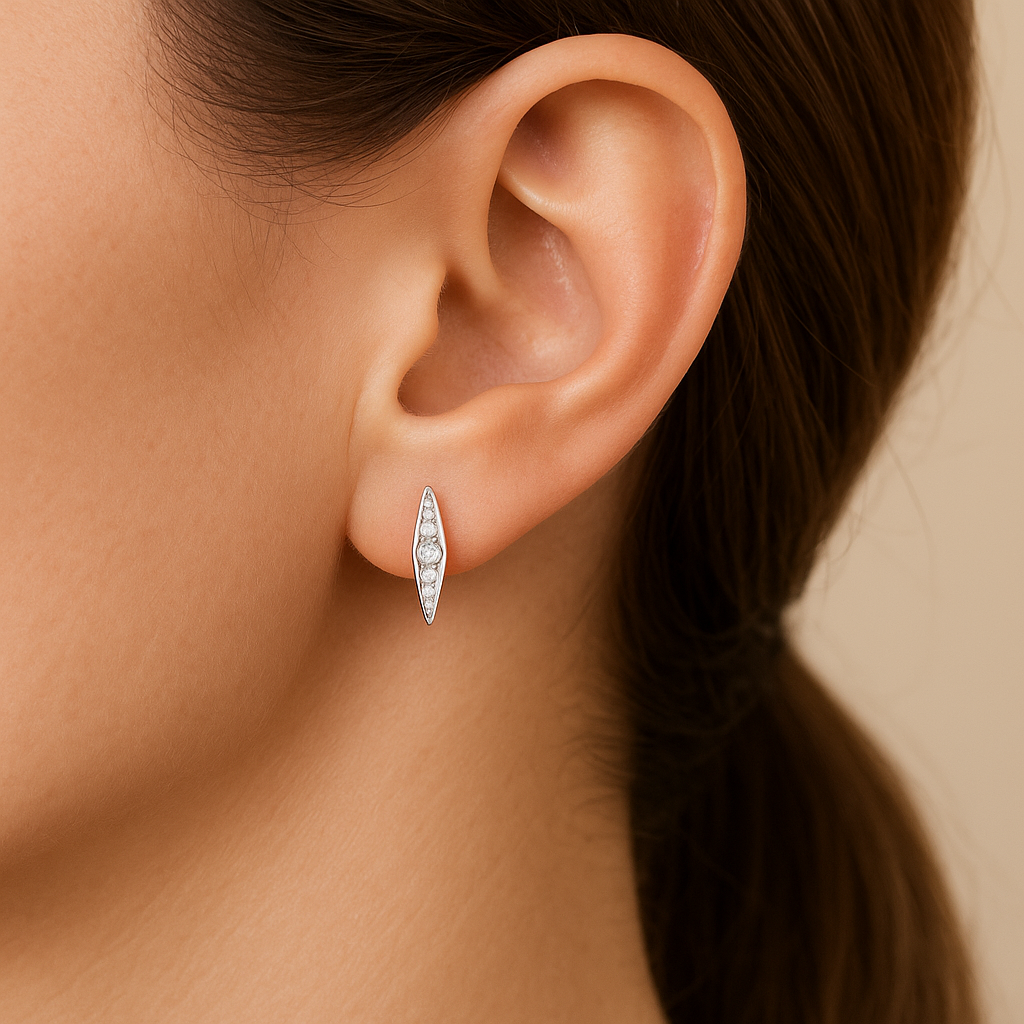 Close-up of an ear wearing a silver earring with a blurred background