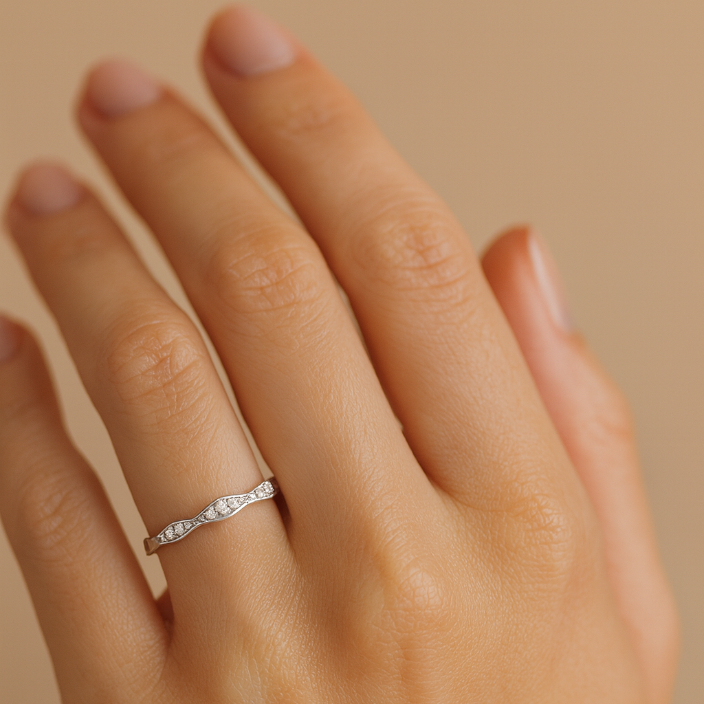 Hand wearing a silver ring with a beige background