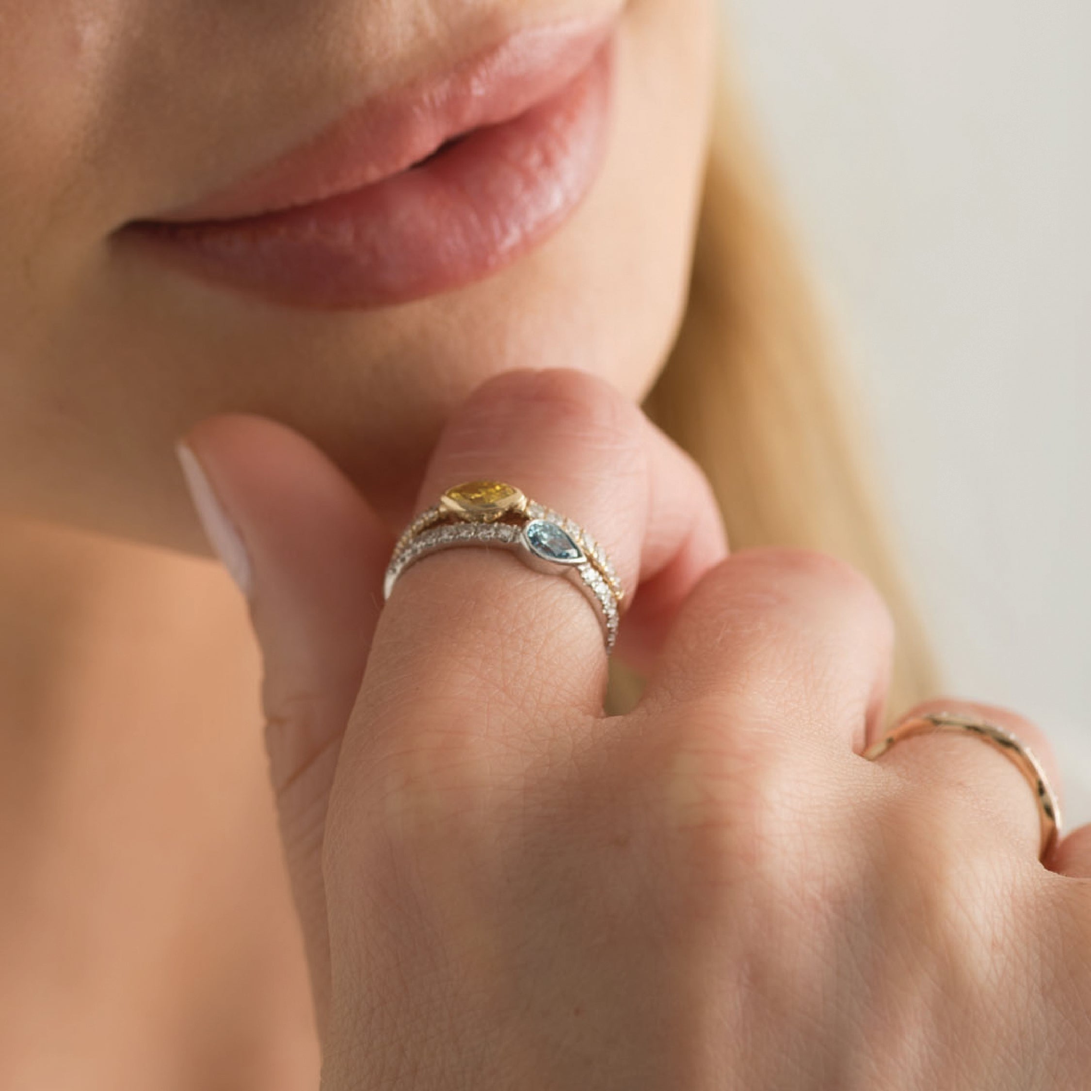 14K white gold ring with blue and yellow diamonds worn on a hand.